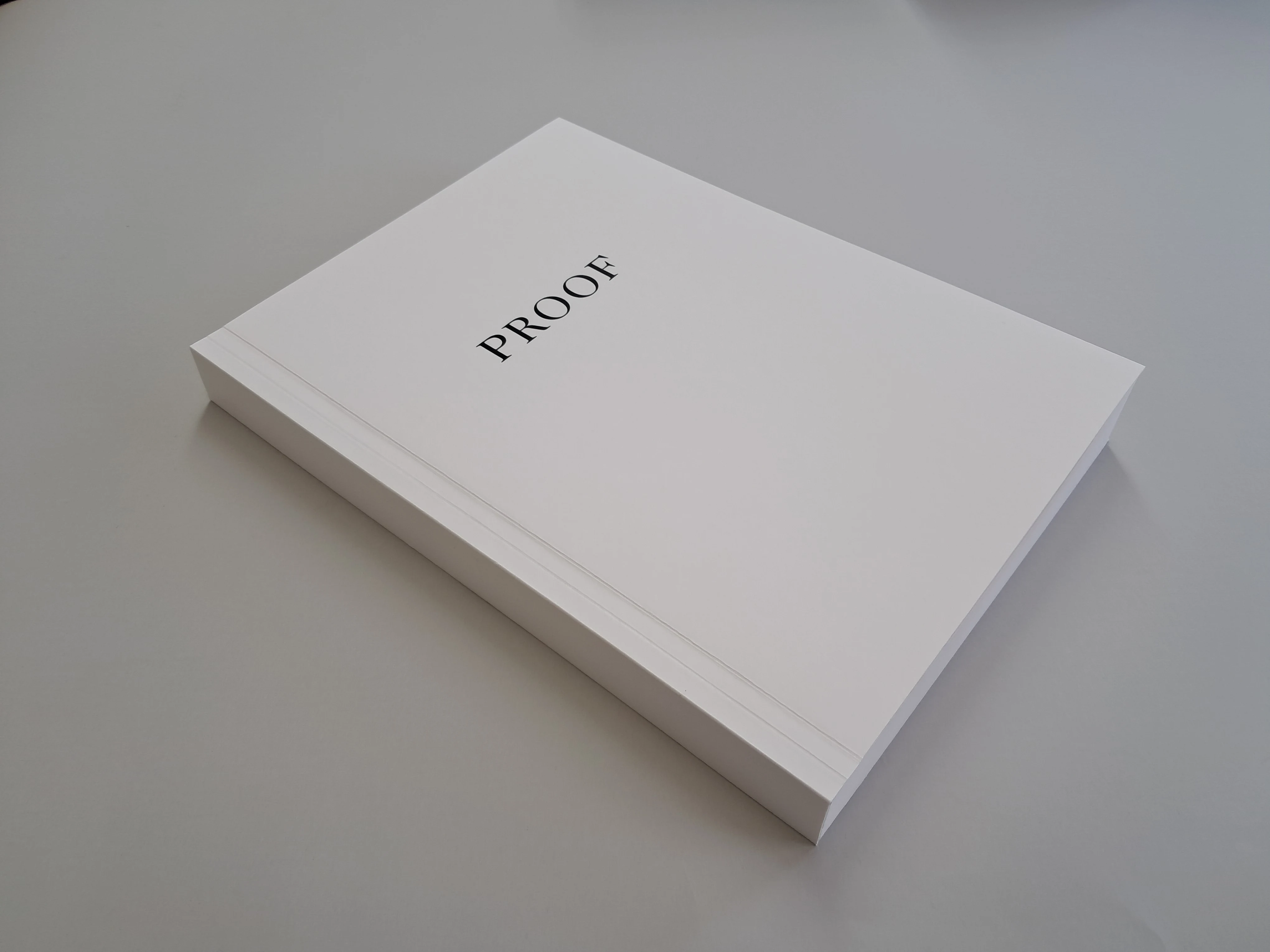 The off-white Proof softcover, viewed at an angle, with black capital lettering and a plain spine.