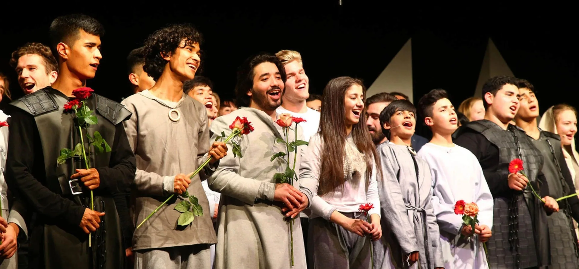 The front row of the company at the curtain call, roses in hand.
